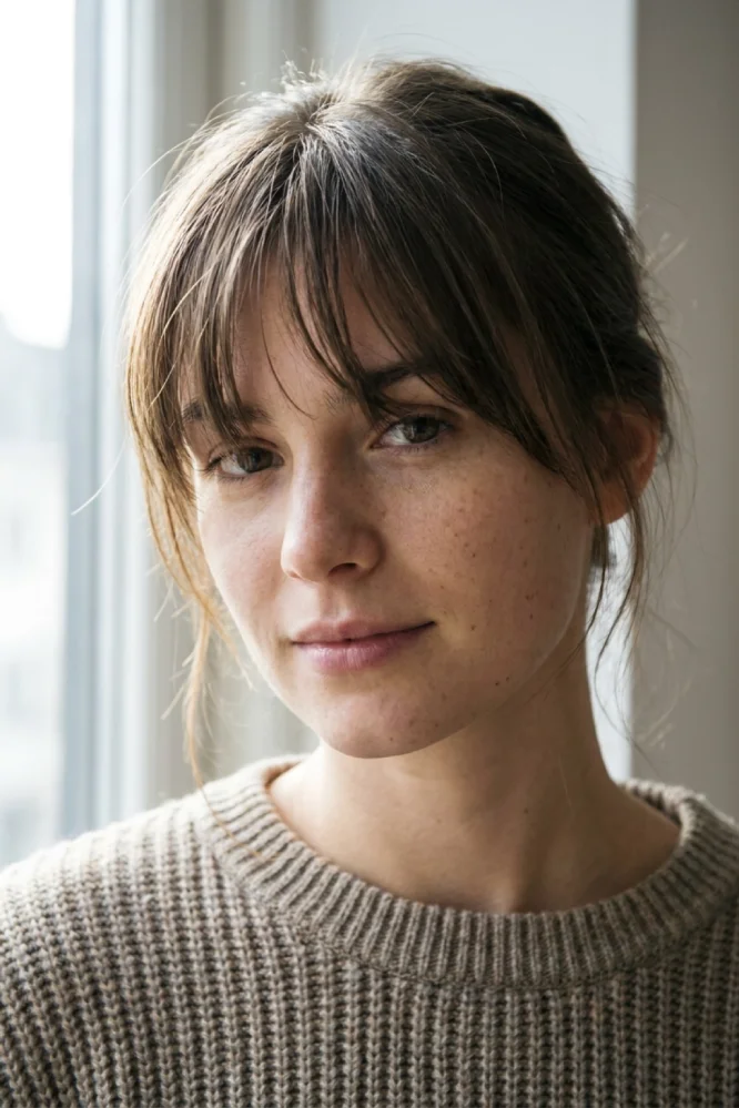 Close-up portrait of a person with feathery, well-defined piecey bangs and natural skin texture.