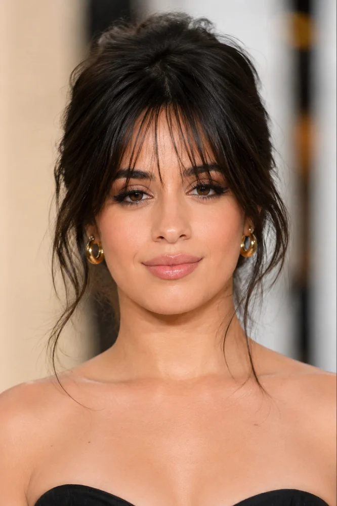 Woman wearing soft wispy bangs with feathered strands across the forehead.